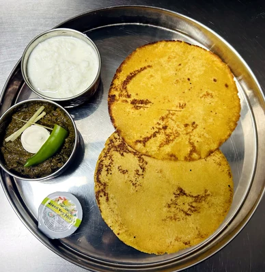 Two flatbreads with white and green side dishes on a metal tray at Lutf Indo-Pak Cuisine
