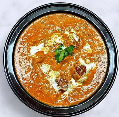 Creamy orange curry garnished with herbs at Lutf Indo-Pak Cuisine