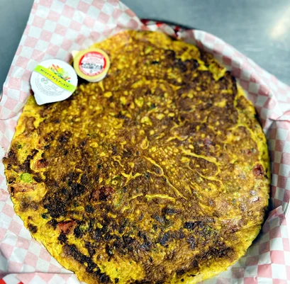 Large freshly cooked flatbread on checked paper at Lutf Indo-Pak Cuisine