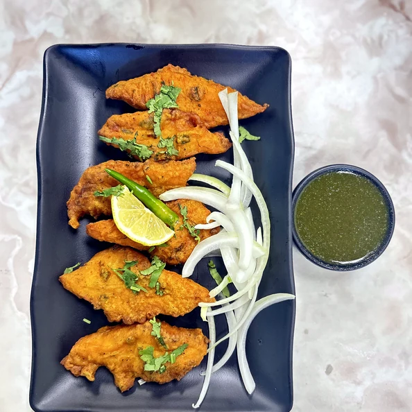 Orange-golden appetizer pieces with onions, lime and green chutney at Lutf Indo-Pak Cuisine