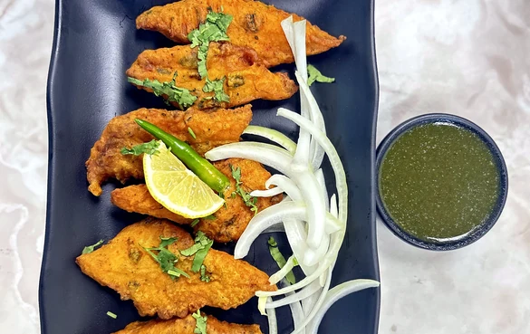 Orange-golden appetizer pieces with onions, lime and green chutney at Lutf Indo-Pak Cuisine