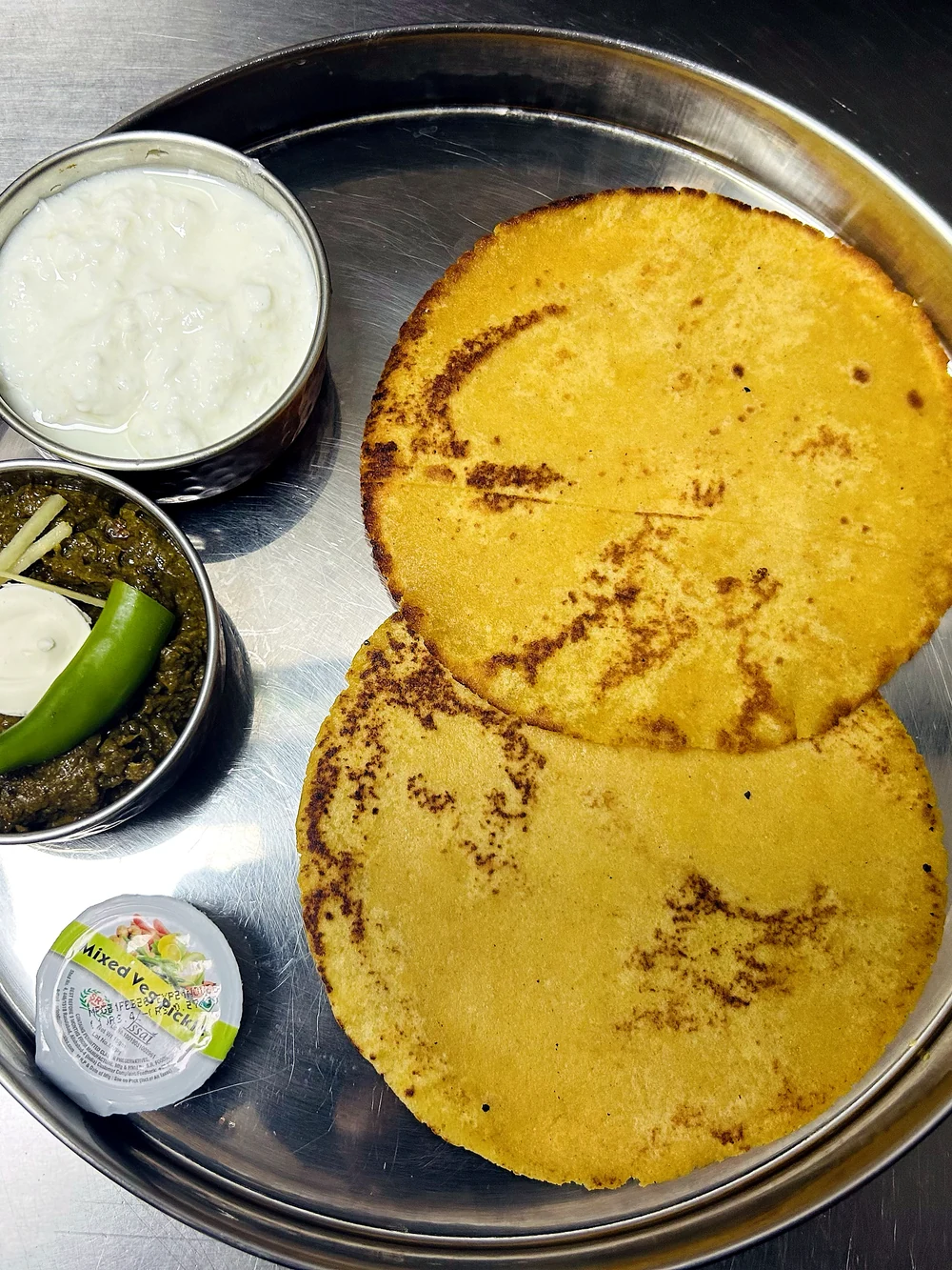 Two flatbreads with white and green side dishes at Lutf Indo-Pak Cuisine